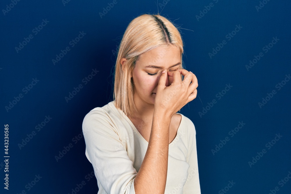 Beautiful blonde woman wearing casual sweater tired rubbing nose and eyes feeling fatigue and headache. stress and frustration concept. Beautiful blonde woman wearing casual sweater tired rubbing nose and eyes feeling fatigue and headache. stress and frustration concept.