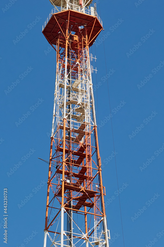 Top part of the TV tower against the background of the summer blue sky. City of Blagoveshchensk, Russia. Top part of the TV tower against the background of the summer blue sky. City of Blagoveshchensk, Russia.