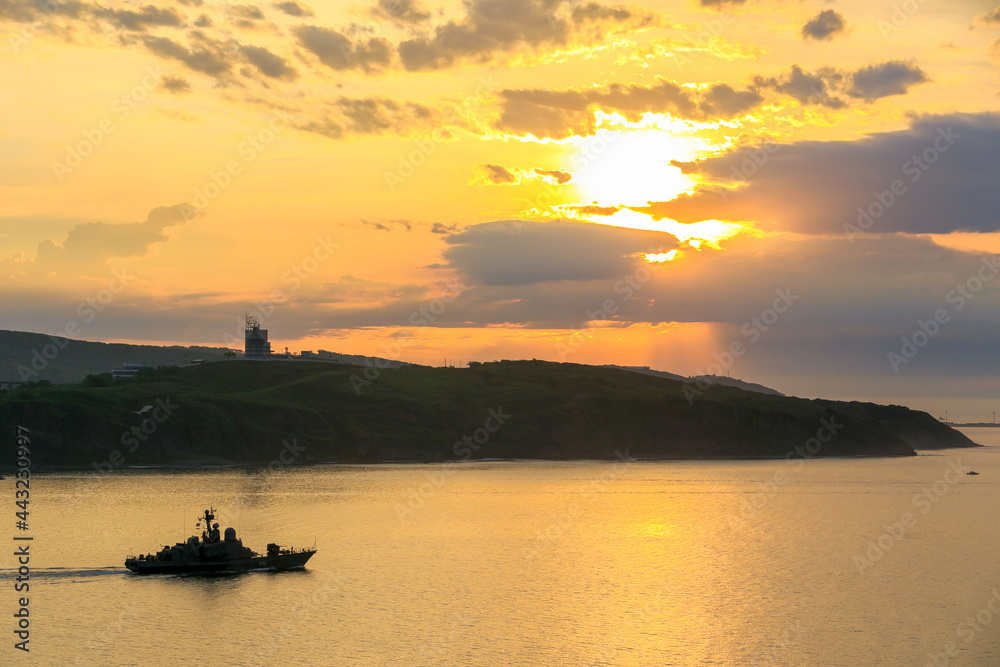 Russian military ship. A warship sails on a mission against the backdrop of dawn in Vladivostok. Ship of the Pacific Fleet.