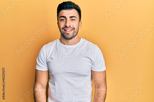 Young hispanic man wearing casual white t shirt with a happy and cool smile on face. lucky person.