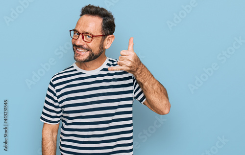 Middle age man wearing casual clothes and glasses smiling doing phone gesture with hand and fingers like talking on the telephone. communicating concepts.