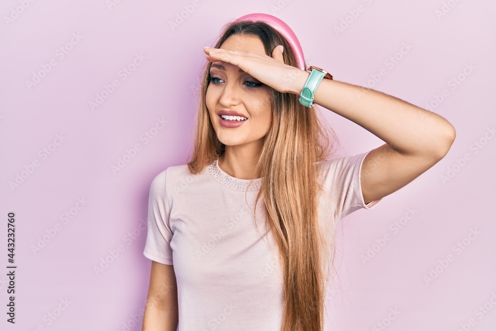 Young blonde girl wearing casual clothes very happy and smiling looking far away with hand over head. searching concept.