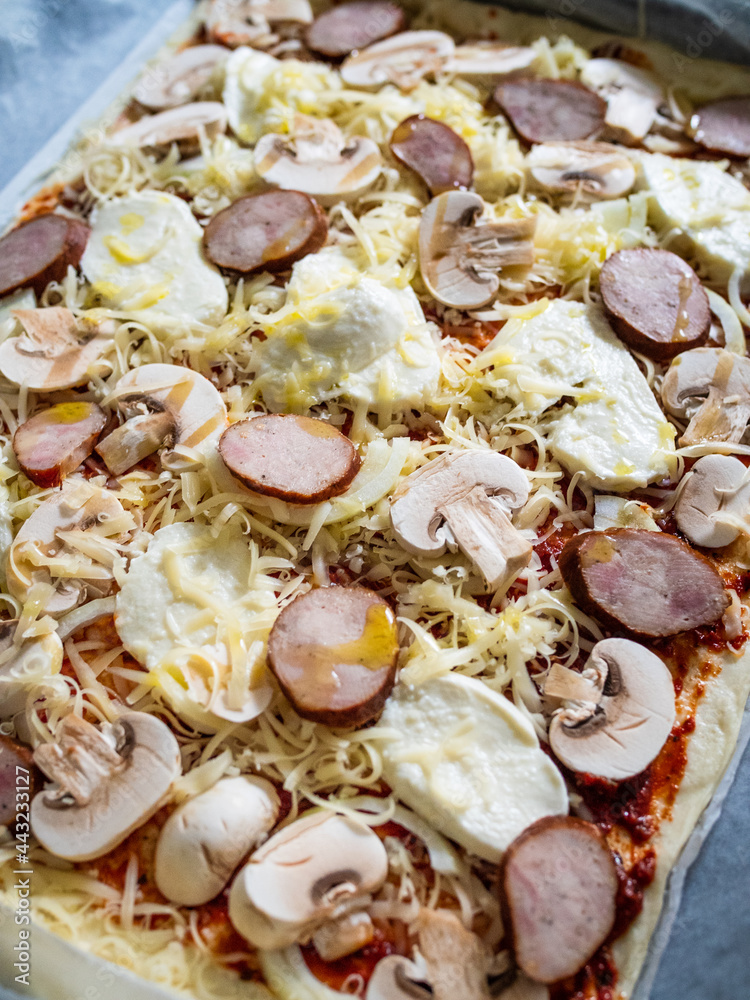 Pizza with white mushrooms, sausage, tomatoes, black olives, parmesan and mozzarella on wooden background
Pizza with white mushrooms, sausage, tomatoes, black olives, parmesan and mozzarella on wooden background