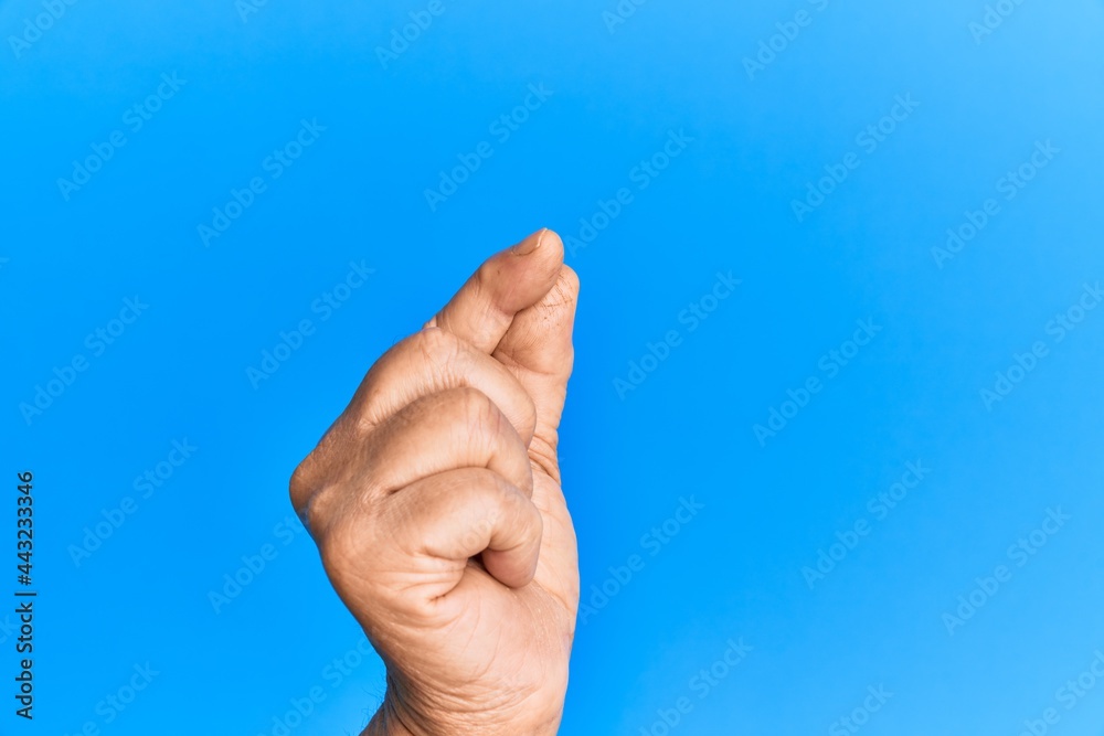 Hand of senior hispanic man over blue isolated background holding blank space with thumb finger, business and advertising Hand of senior hispanic man over blue isolated background holding blank space with thumb finger, business and advertising
