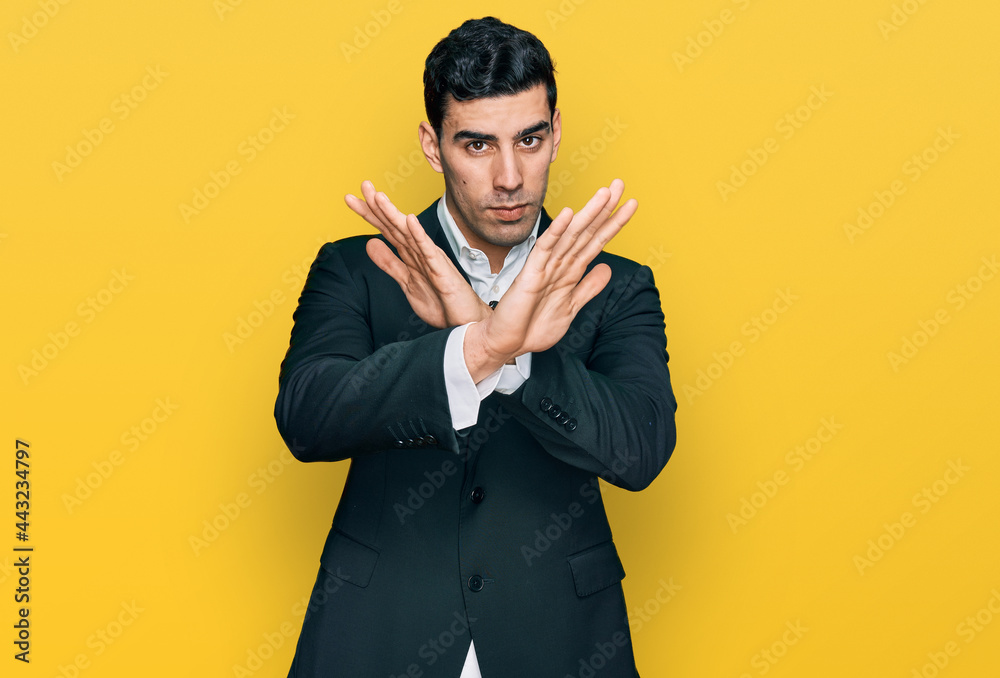Handsome hispanic man wearing business clothes rejection expression crossing arms doing negative sign, angry face Handsome hispanic man wearing business clothes rejection expression crossing arms doing negative sign, angry face