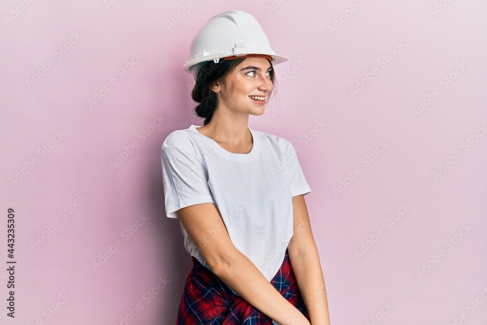 Young caucasian woman wearing hardhat looking away to side with smile on face, natural expression. laughing confident. Young caucasian woman wearing hardhat looking away to side with smile on face, natural expression. laughing confident.