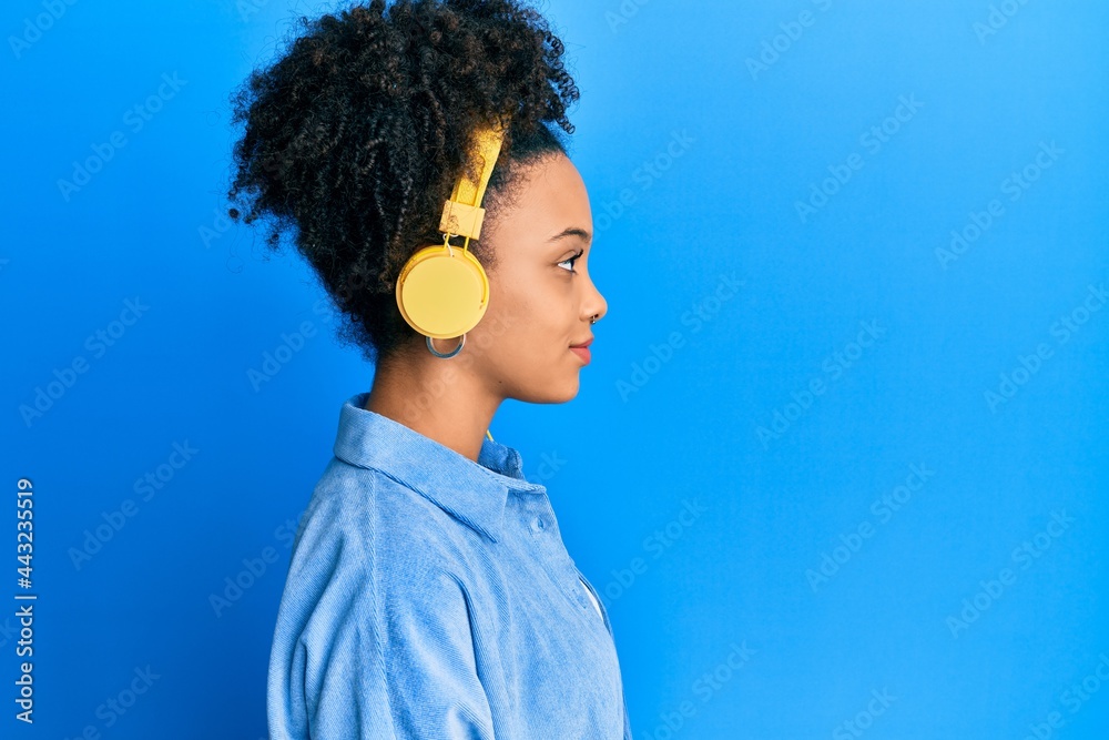 Young african american girl listening to music using headphones looking