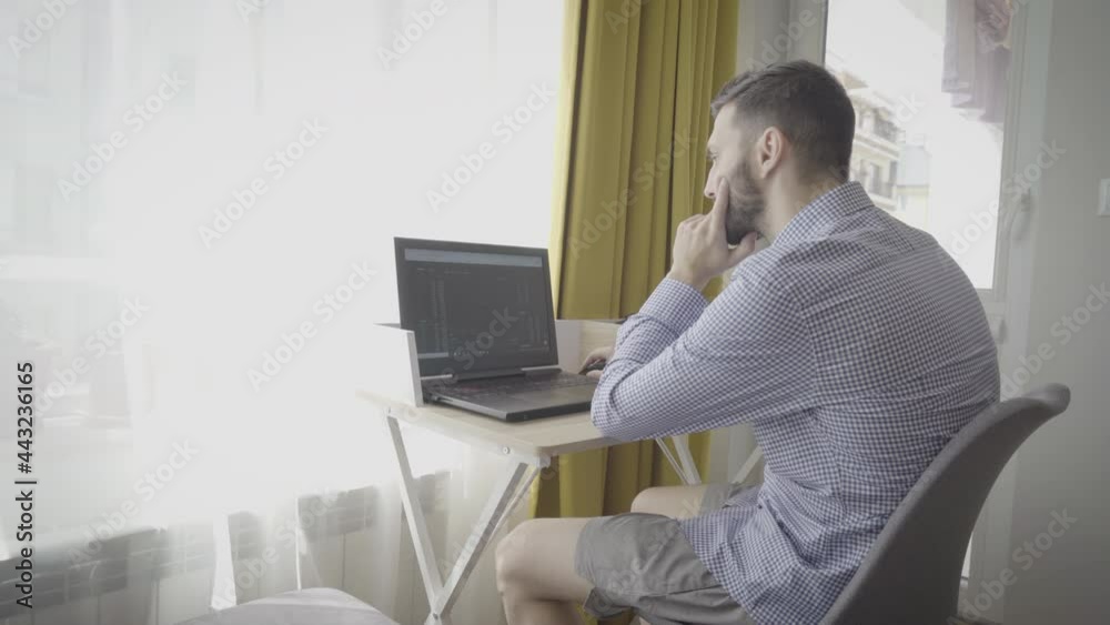 Thoughtful trader in formalwear looking at trading charts and financial data at home