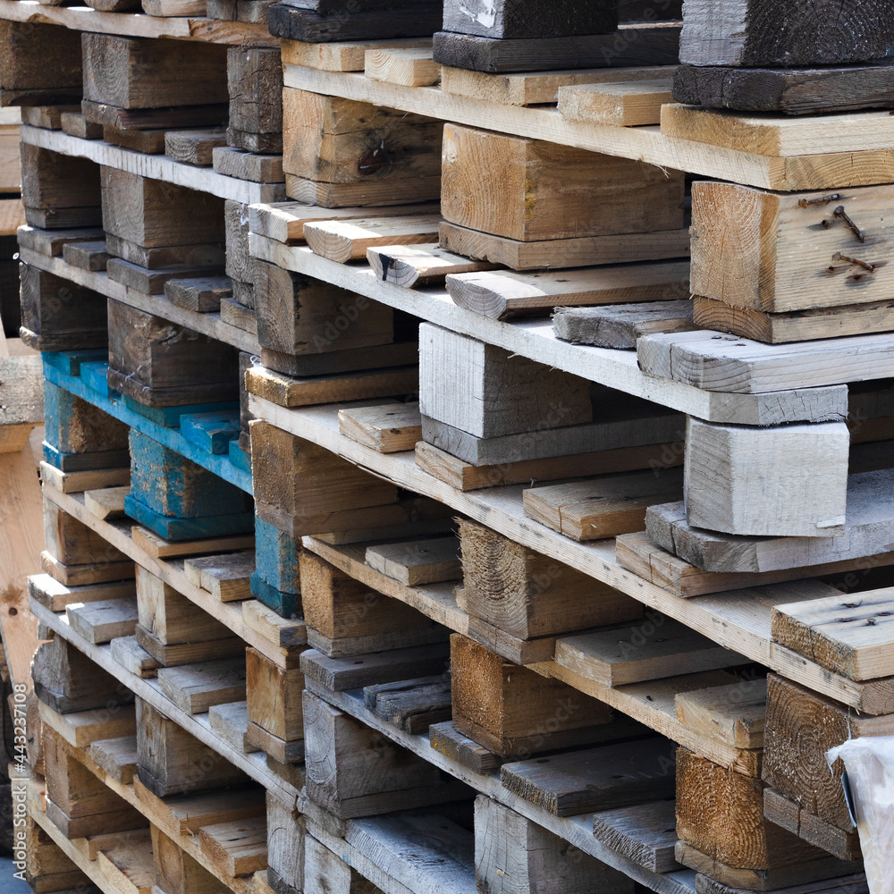 A stack of old wooden pallets for loading. Logistics and cargo delivery. Square background A stack of old wooden pallets for loading. Logistics and cargo delivery. Square background