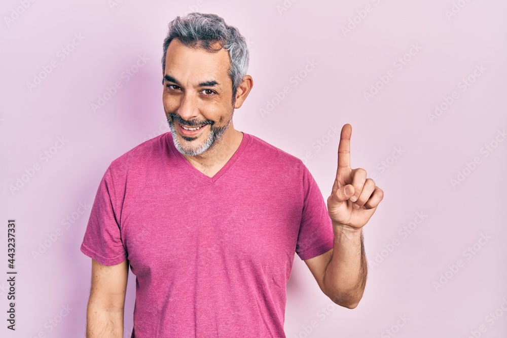 Handsome middle age man with grey hair wearing casual pink t shirt smiling with an idea or question pointing finger up with happy face, number one Handsome middle age man with grey hair wearing casual pink t shirt smiling with an idea or question pointing finger up with happy face, number one