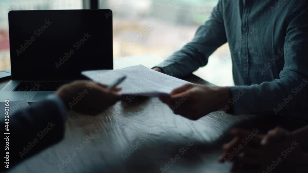 Close-up hands of unrecognizable two businesspeople signing agreement sitting at table with documents and laptop. Happy young couple taking financial advice signing paper document.