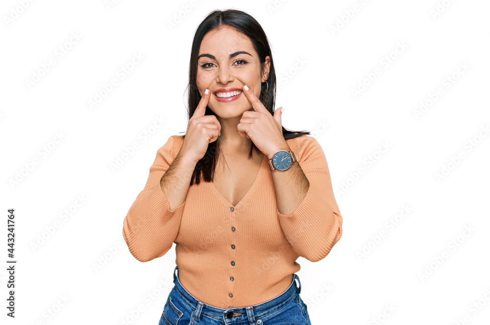 Young hispanic woman wearing casual clothes smiling with open mouth, fingers pointing and forcing cheerful smile Young hispanic woman wearing casual clothes smiling with open mouth, fingers pointing and forcing cheerful smile