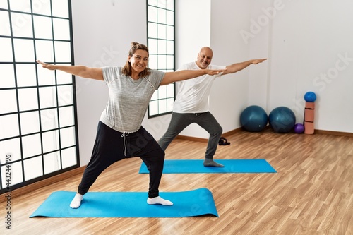 Middle age hispanic couple stretching at sport center.