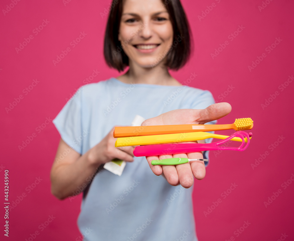 Beautiful young woman uses an oral care kit consisting of a tongue scraper, single tufted and interdental brush Beautiful young woman uses an oral care kit consisting of a tongue scraper, single tufted and interdental brush