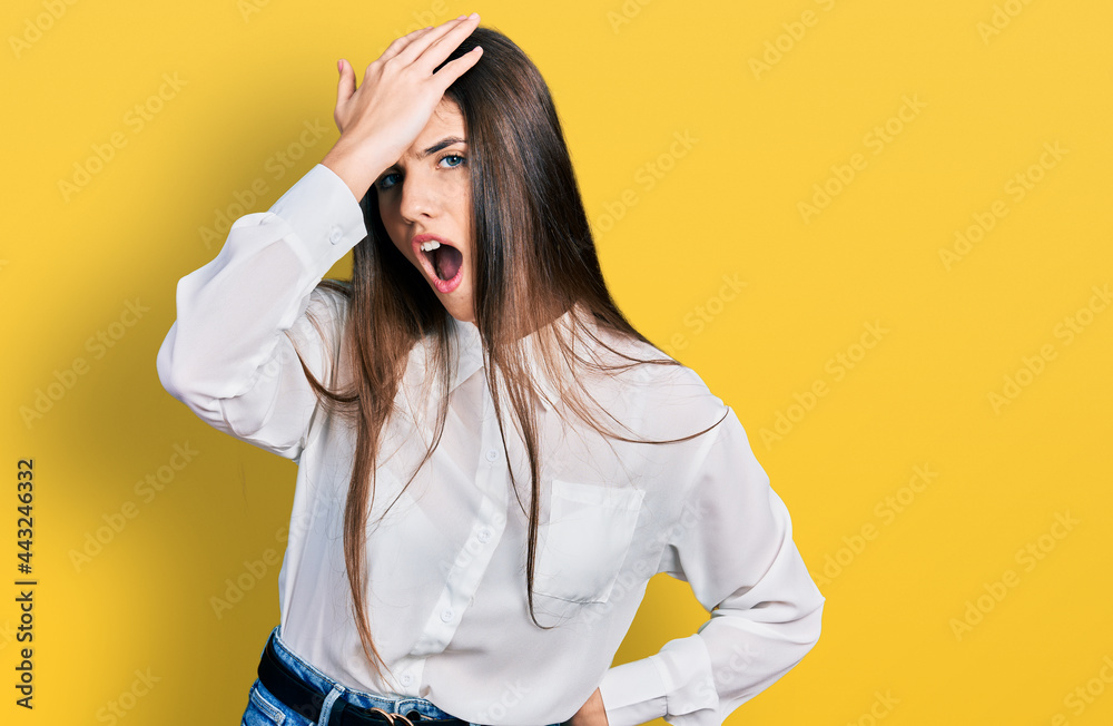 Young brunette teenager wearing business white shirt surprised with hand on head for mistake, remember error. forgot, bad memory concept. Young brunette teenager wearing business white shirt surprised with hand on head for mistake, remember error. forgot, bad memory concept.