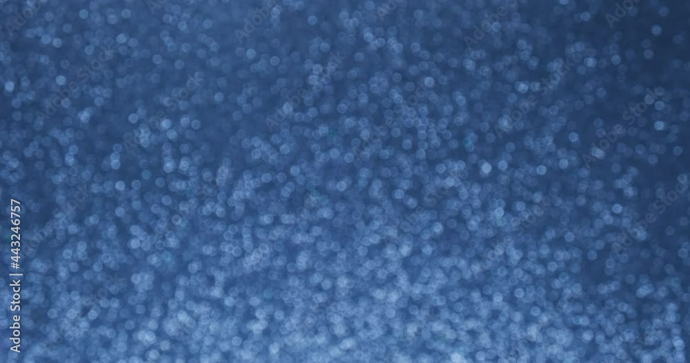 Glittering abstract blue bokeh background. Smoothly increase and decrease the flickering of blue lights. Holiday concept backdrop. Defocused blue particles Glittering abstract blue bokeh background. Smoothly increase and decrease the flickering of blue lights. Holiday concept backdrop. Defocused blue particles