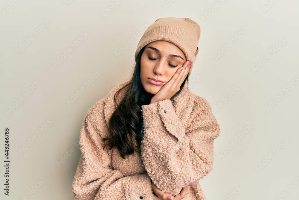 Young hispanic woman wearing wool sweater and winter hat thinking looking tired and bored with depression problems with crossed arms.