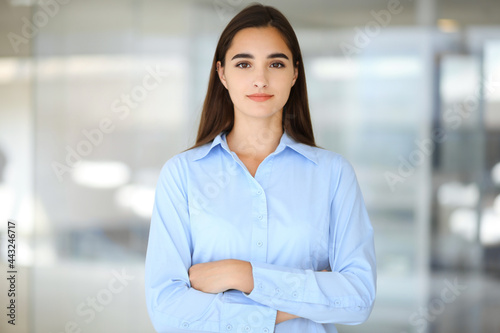 A friendly young businesswoman or female student is standing with some papers in the office. Lifestyle and diverse people concept