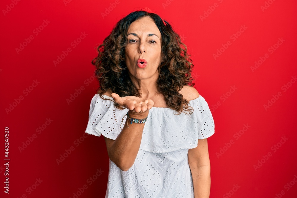 Middle age hispanic woman wearing casual clothes looking at the camera blowing a kiss with hand on air being lovely and sexy. love expression. Middle age hispanic woman wearing casual clothes looking at the camera blowing a kiss with hand on air being lovely and sexy. love expression.