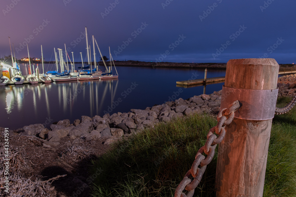 Obraz premium Wodden posts hold the large chain links firmly in place as a barrier around the Ventura marina water.