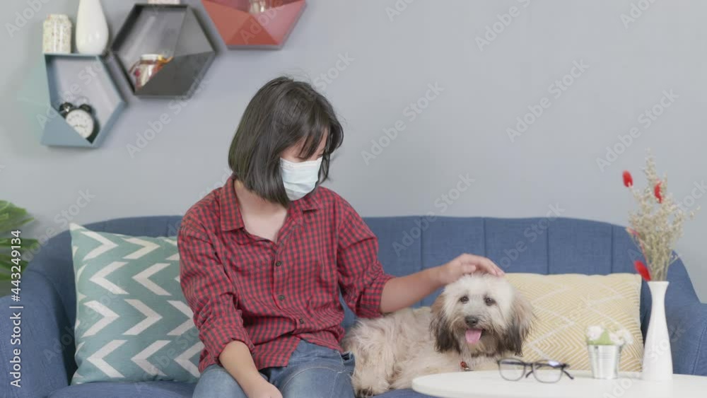 asian kid wearing face masks, sitting on sofa holding pet dog, Social distancing during Covid 19 Coronavirus quarantine lockdown. asian kid wearing face masks, sitting on sofa holding pet dog, Social distancing during Covid 19 Coronavirus quarantine lockdown.