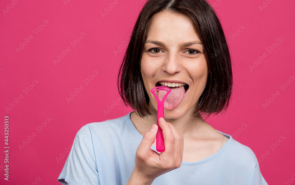 Beautiful happy young woman with tongue scraper on blank pink background Beautiful happy young woman with tongue scraper on blank pink background