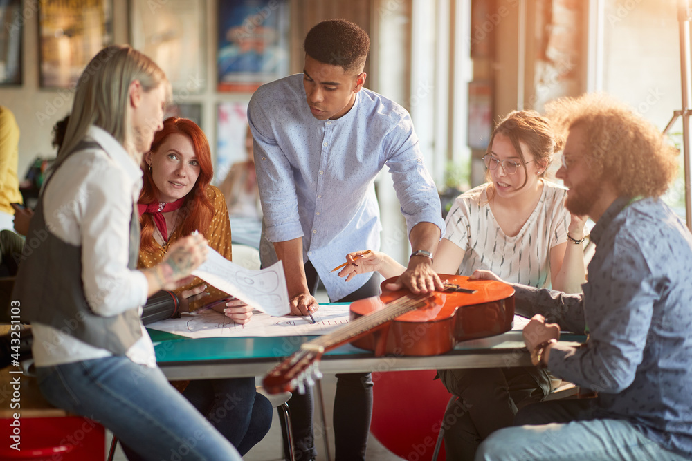 Group of young creative people in the office are discussing about a draft of a new guitar design