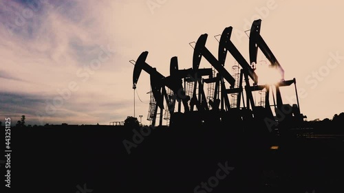 Silhouette of oil extracting operation by pump jack in the oil field