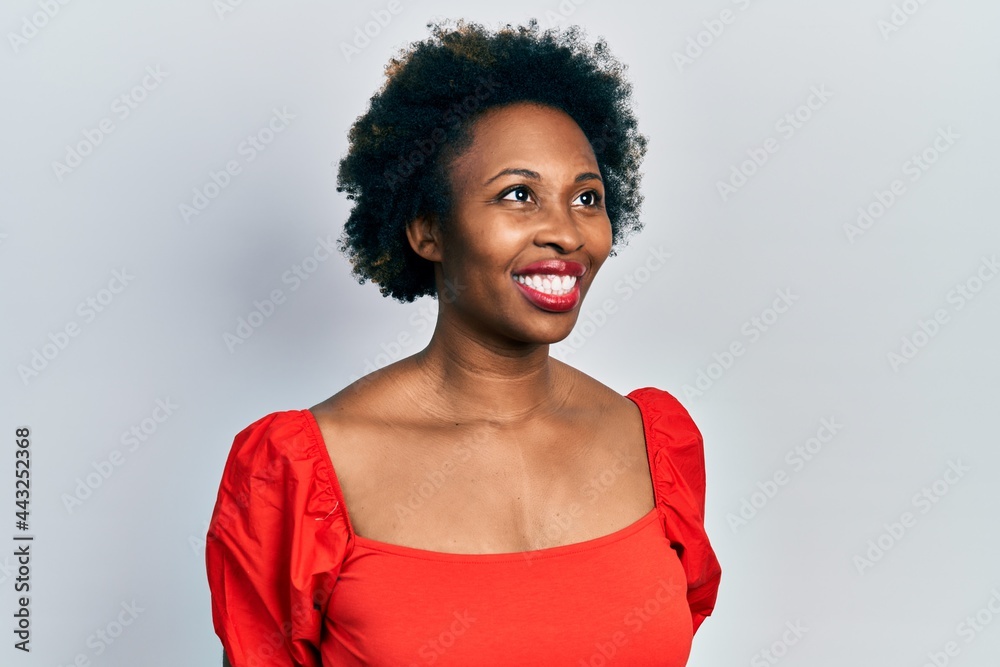 Young african american woman wearing casual clothes looking away to side with smile on face, natural expression. laughing confident. Young african american woman wearing casual clothes looking away to side with smile on face, natural expression. laughing confident.