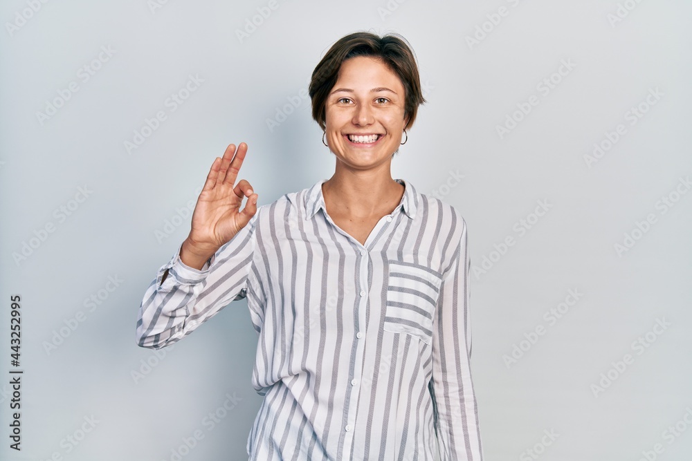Young caucasian woman wearing casual clothes doing ok sign with fingers, smiling friendly gesturing excellent symbol Young caucasian woman wearing casual clothes doing ok sign with fingers, smiling friendly gesturing excellent symbol