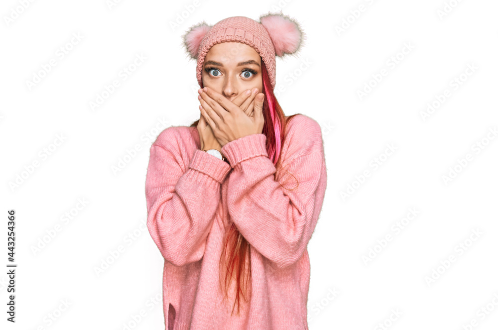 Young caucasian woman wearing casual clothes and wool cap shocked covering mouth with hands for mistake. secret concept. Young caucasian woman wearing casual clothes and wool cap shocked covering mouth with hands for mistake. secret concept.