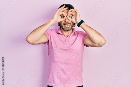Middle age caucasian man wearing casual white t shirt doing ok gesture like binoculars sticking tongue out, eyes looking through fingers. crazy expression.