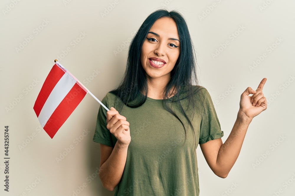 Young hispanic girl holding austria flag smiling happy pointing with hand and finger to the side Young hispanic girl holding austria flag smiling happy pointing with hand and finger to the side