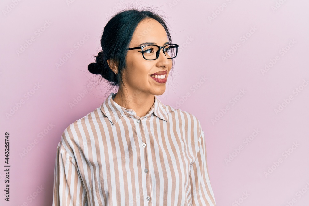 Young hispanic girl wearing casual clothes and glasses looking to side, relax profile pose with natural face and confident smile.