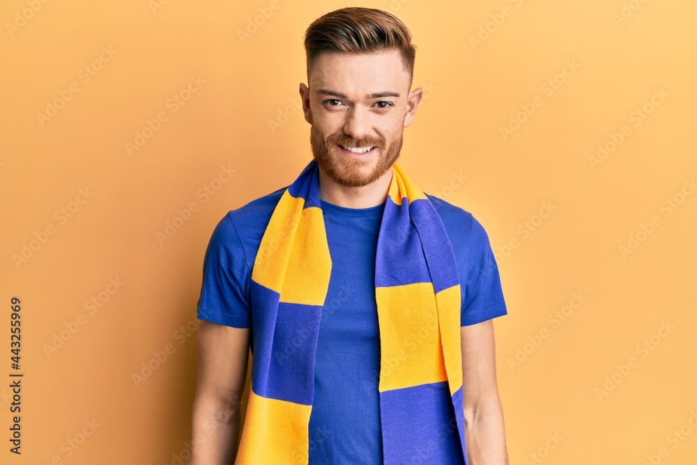 Young redhead man football hooligan cheering game with a happy and cool smile on face. lucky person. Young redhead man football hooligan cheering game with a happy and cool smile on face. lucky person.