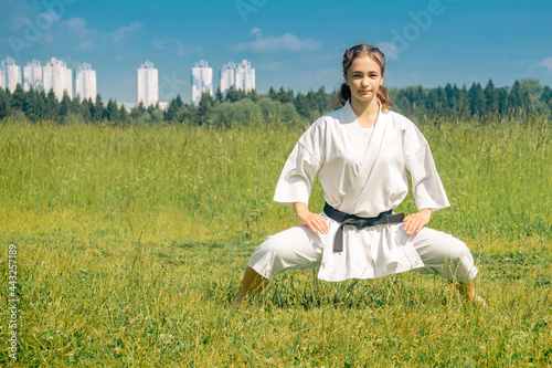 Bild auf Leinwand teen girl practicing karate kata outdoors in kiba-dachi stance