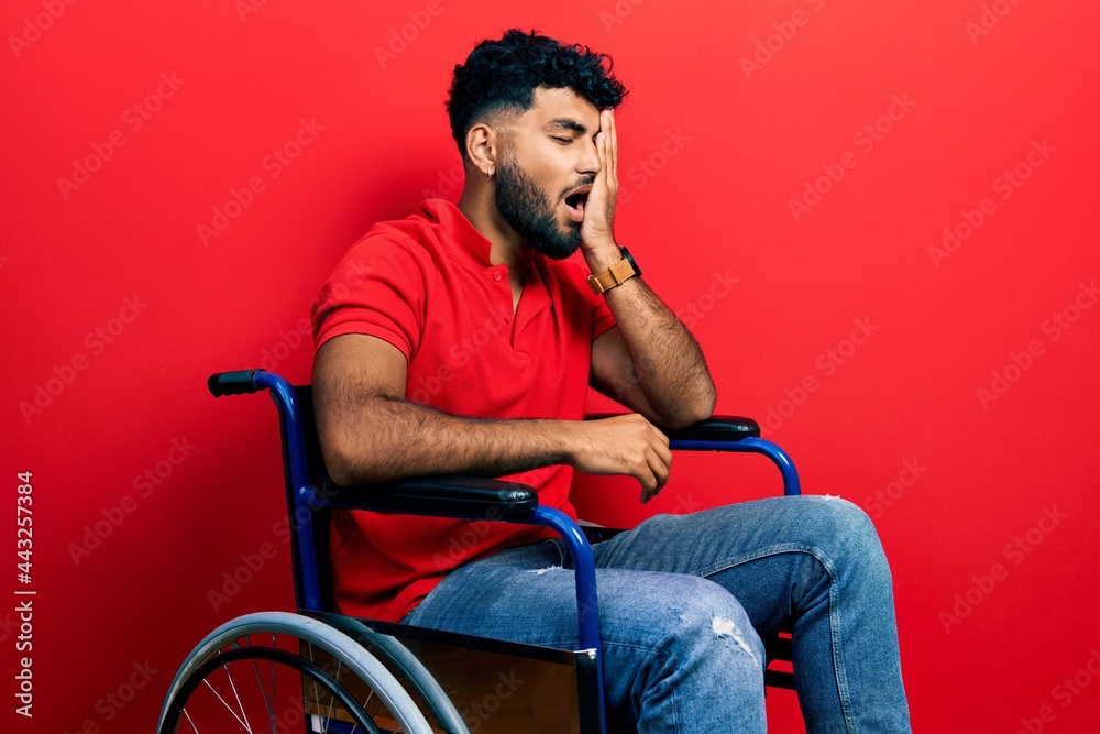 Arab man with beard sitting on wheelchair yawning tired covering half face, eye and mouth with hand. face hurts in pain. Arab man with beard sitting on wheelchair yawning tired covering half face, eye and mouth with hand. face hurts in pain.