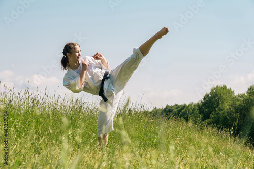 teen girl training karate kata outdoors, performs the mawashi geri kick photo
