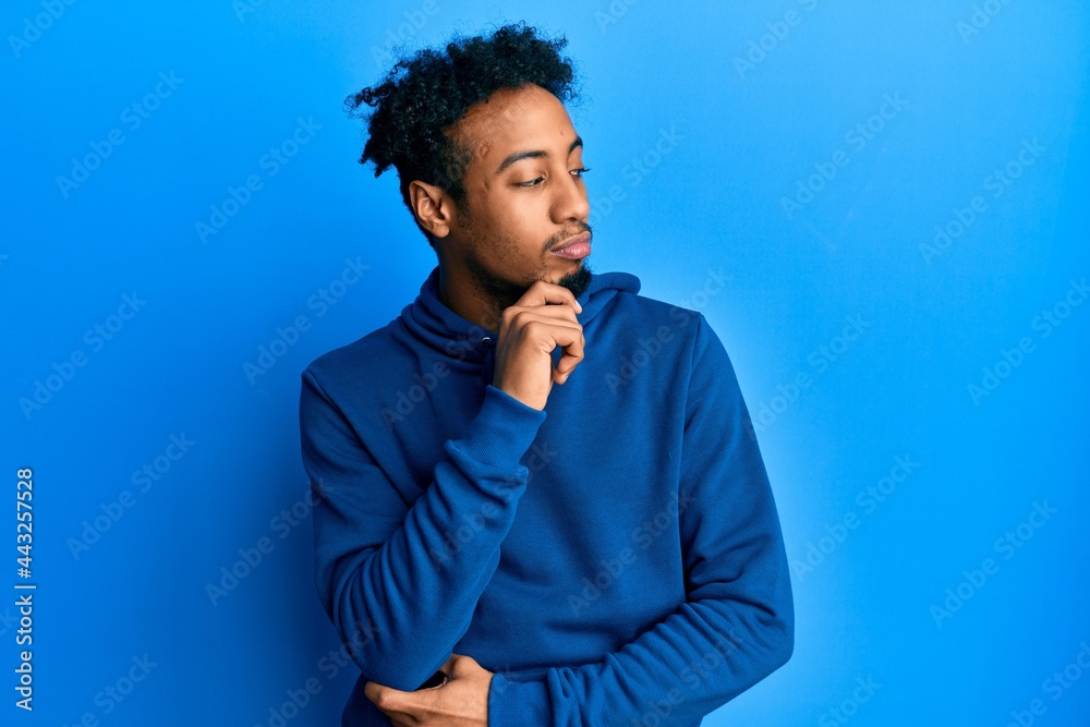 Young african american man with beard wearing casual sweatshirt thinking concentrated about doubt with finger on chin and looking up wondering Young african american man with beard wearing casual sweatshirt thinking concentrated about doubt with finger on chin and looking up wondering