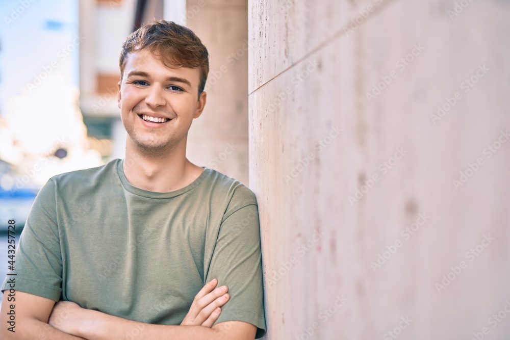 Obraz premium Young caucasian man with arms crossed smiling happy at the city.
