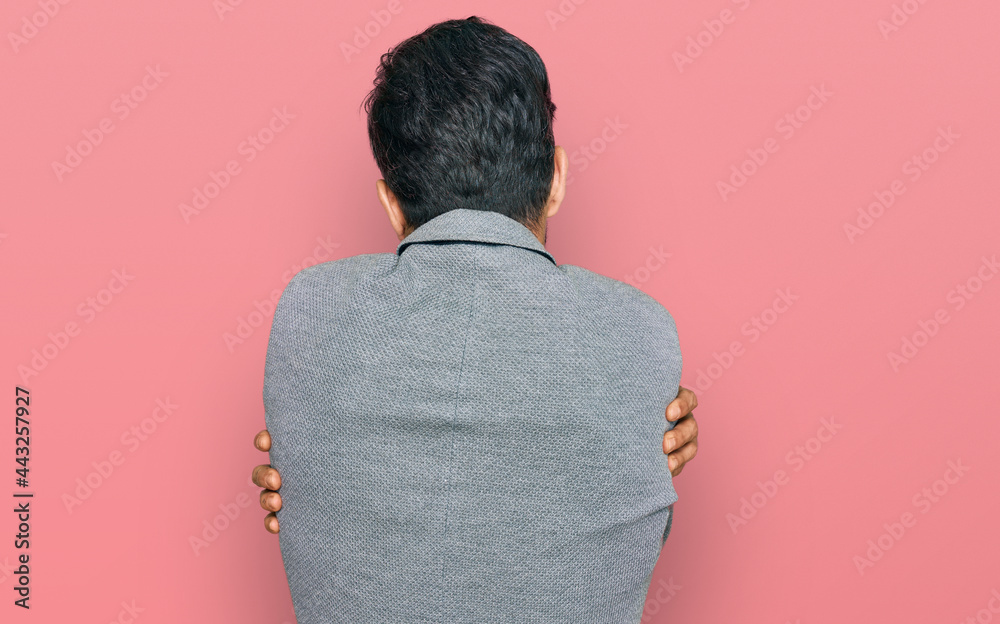 Young hispanic man wearing business clothes hugging oneself happy and positive from backwards. self love and self care Young hispanic man wearing business clothes hugging oneself happy and positive from backwards. self love and self care
