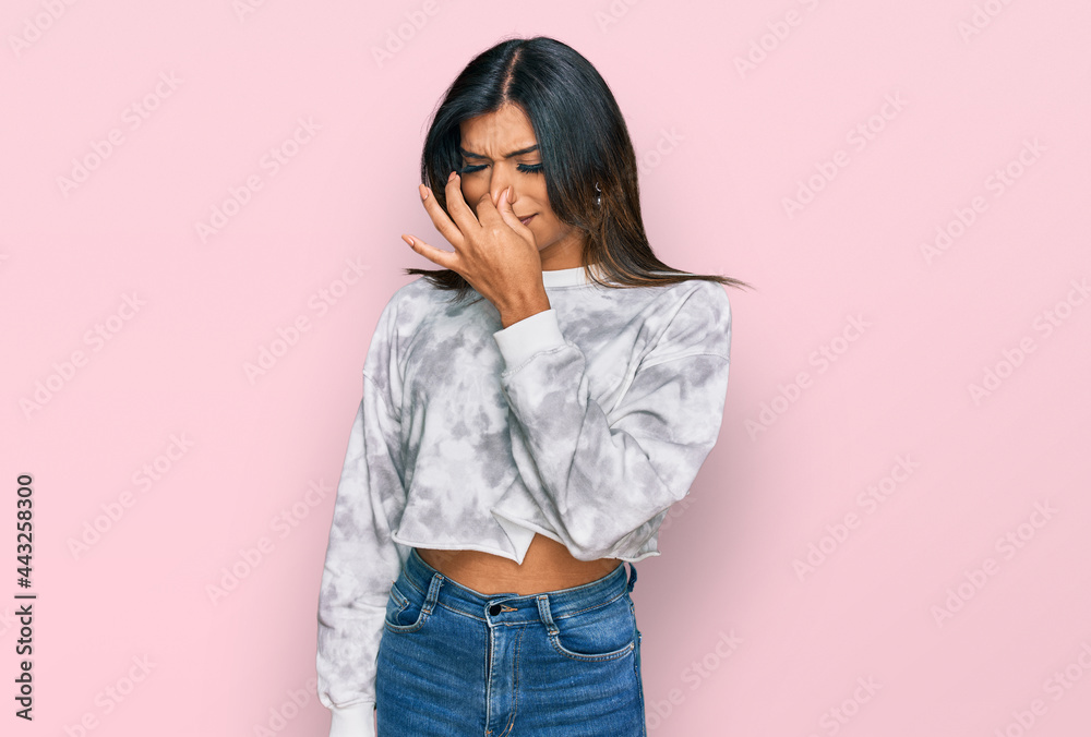 Young latin transsexual transgender woman wearing casual clothes smelling something stinky and disgusting, intolerable smell, holding breath with fingers on nose. bad smell Young latin transsexual transgender woman wearing casual clothes smelling something stinky and disgusting, intolerable smell, holding breath with fingers on nose. bad smell