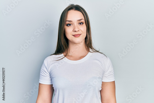 Young hispanic girl wearing casual white t shirt with a happy and cool smile on face. lucky person.