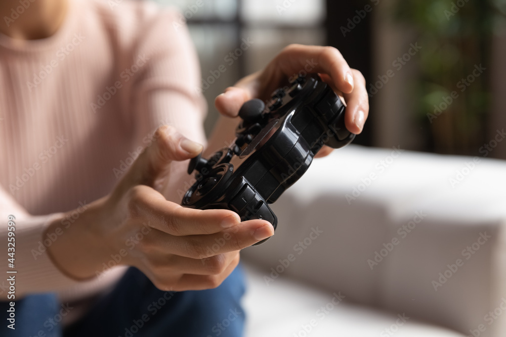 Close up cropped image young woman holding remote controller in hands, having fun playing online console video game, involved in virtual reality, entertaining alone on weekend at home, hobby concept.