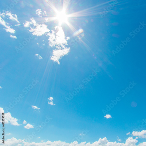 Fototapeta Naklejka Na Ścianę i Meble -  Natural abstract warm background of bright blue sky and fluffy white clouds on a sunny, light a flare and sun.