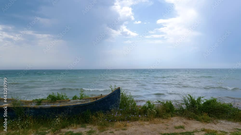 Old wooden fishing boat on the seashore. Rain in the open sea. Beautiful sea side landscape. Fishing boat wreck on the beach. The storm on the seashore is approaching. Wild beach Romania Old wooden fishing boat on the seashore. Rain in the open sea. Beautiful sea side landscape. Fishing boat wreck on the beach. The storm on the seashore is approaching. Wild beach Romania