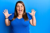 Beautiful brunette plus size woman wearing casual blue t shirt celebrating crazy and amazed for success with arms raised and open eyes screaming excited. winner concept