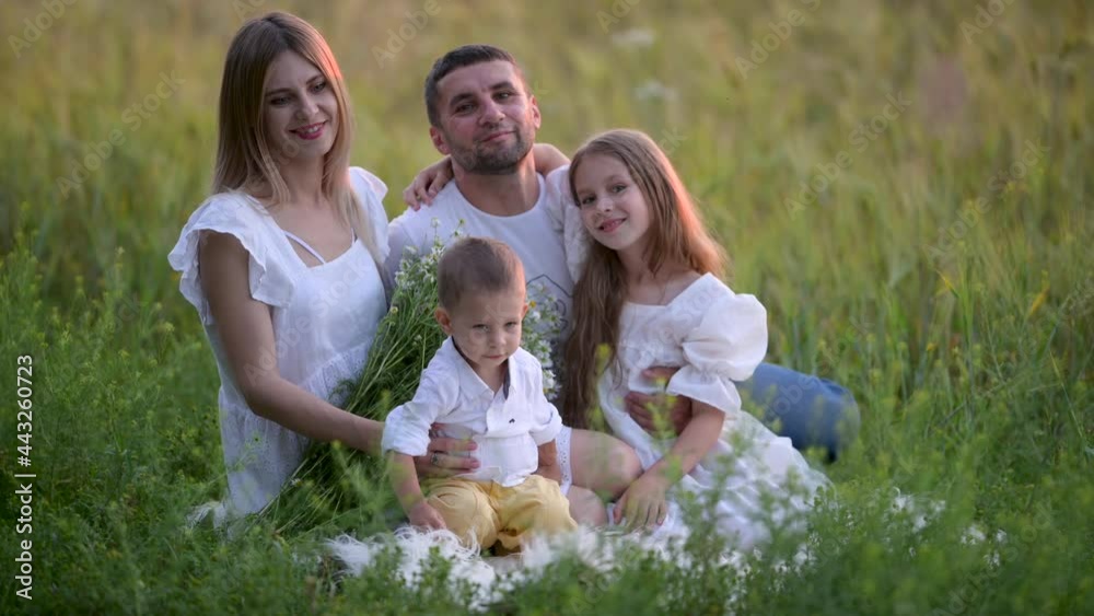 Happy smiling family resting on a green meadow. Mother, father and children having fun on summer day. Happy family outdoors Happy smiling family resting on a green meadow. Mother, father and children having fun on summer day. Happy family outdoors