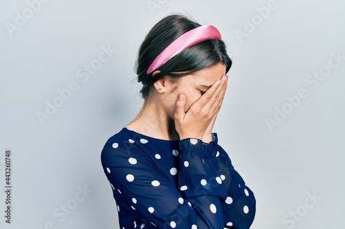 Young brunette girl wearing elegant look with sad expression covering face with hands while crying. depression concept.