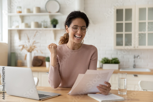 Quadro em tela Emotional happy young woman in glasses reading paper correspondence letter with good news, celebrating getting excellent test results, last mortgage payment notification, feeling overjoyed in kitchen
